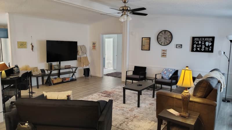 Spacious living room with leather sofa, loveseat, accent armchairs, flat-screen TV, and wood-look flooring at Lichner Resort Stays