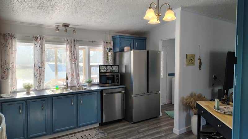 Kitchen with slate blue cabinets, stainless steel French-door refrigerator, double sink, and brass chandelier at Lichner Resort Stays