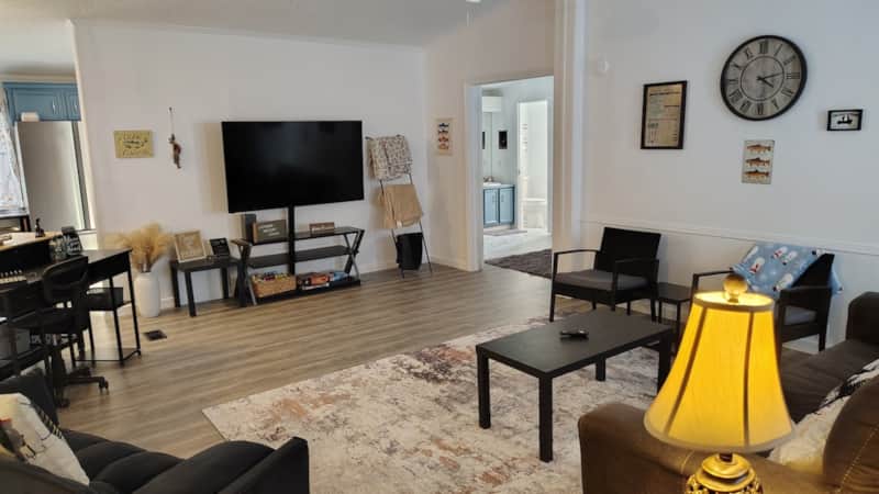 Open-concept living room with leather sofa, recliner, flat-screen TV, board game storage, and blanket ladder at Lichner Resort Stays