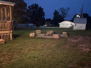 Outdoor fire pit with boulder seating at Lichner Resort Stays at dusk